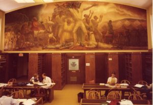 A color photo of students studying underneath the Curry mural.