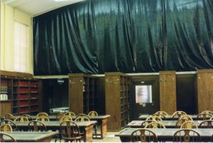 A color photo of the Curry mural covered up by a large black tarp during construction on the Law Library in the 1990s.